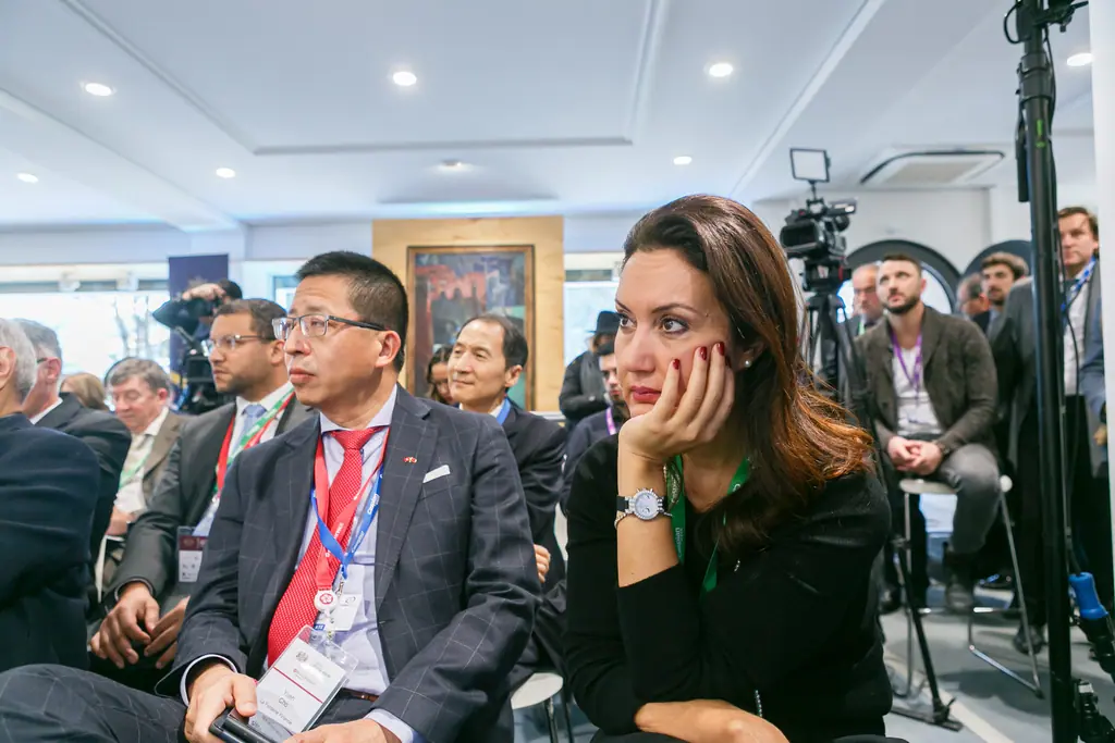 Two members of the audience listen closely during a roundtable, one resting her chin on her hand
