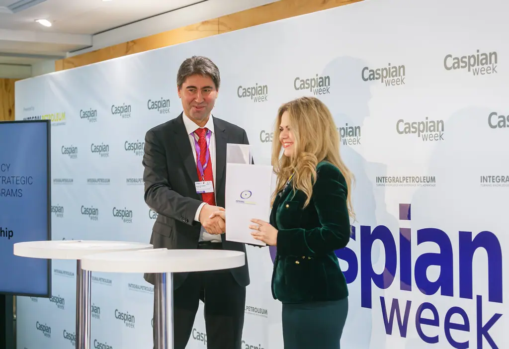 Two signatories shake hands over a signed document