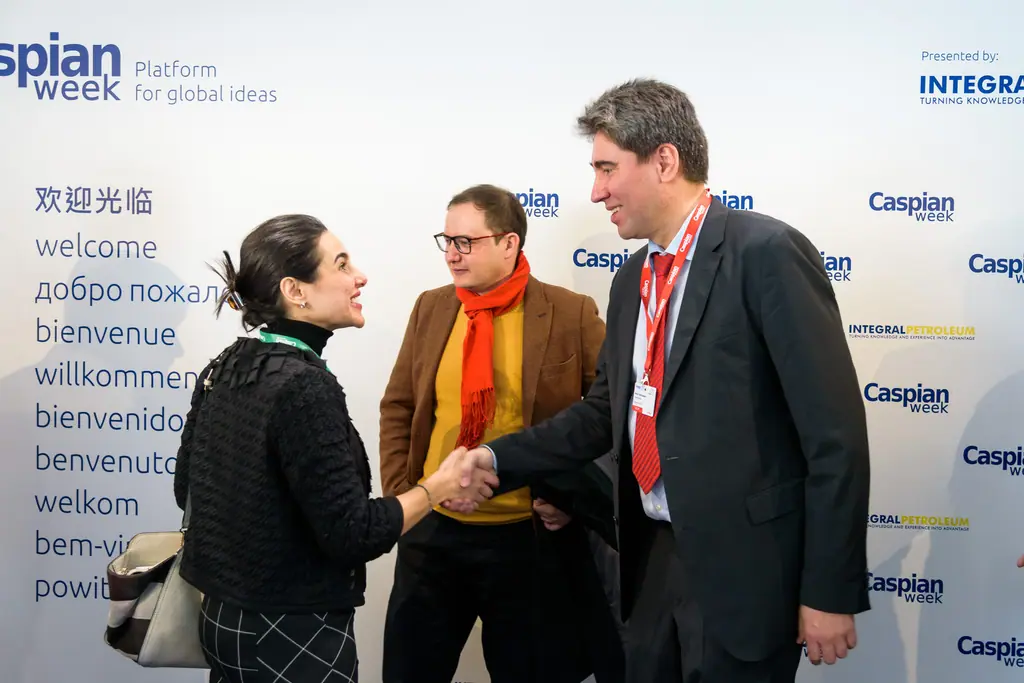 Guests shake hands in front of a wall that says welcome in a dozen languages