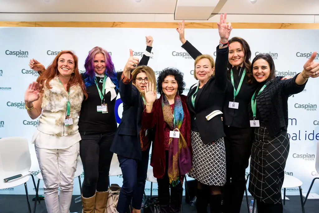 Panellists of the women’s leadership session celebrate on stage, arms raised
